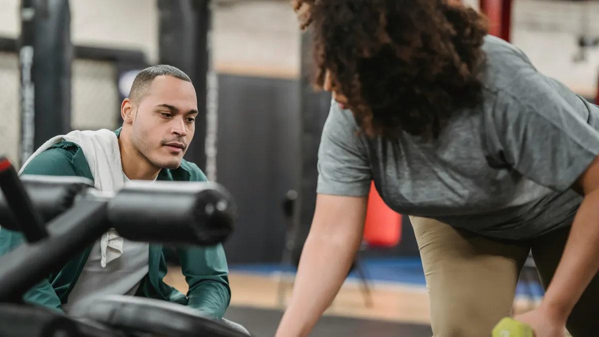 Personal trainer coaching client with dumbbells at Prosper TX gym